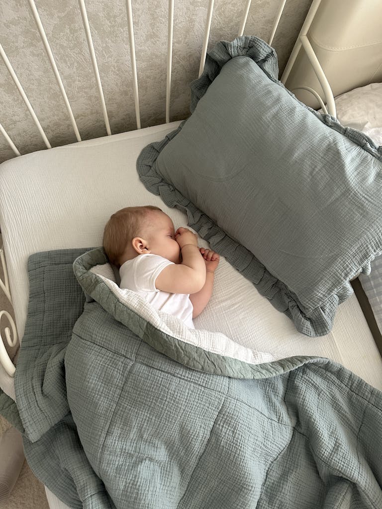 A serene baby sleeping in a crib under soft bedding, creating a cozy atmosphere.